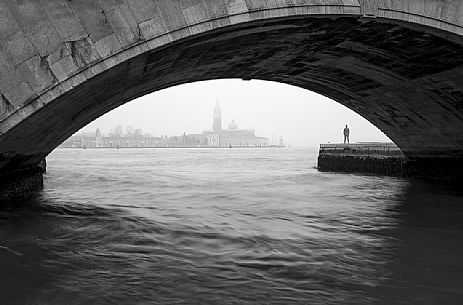 View of Basilica of St Giorgio Maggiore photographed from under the bridge in a foggy day