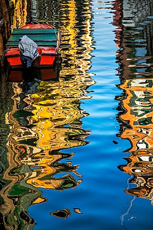 The colors of the reflections of gondolas and Venetian houses on the canal in a sunny day