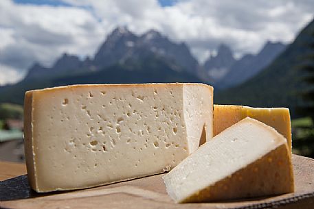 Typical cheese, in the background the Dolomites of Sesto