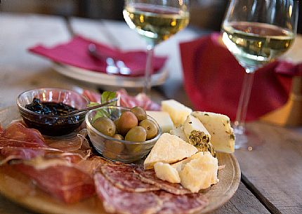 Cutting board of ham, salami and cheese with two glasses of white wine from Friuli