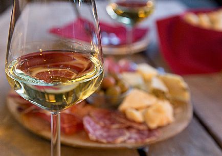 Cutting board of ham, salami and cheese with two glasses of white wine from Friuli