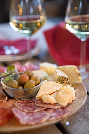 Cutting board of ham, salami and cheese with two glasses of white wine from Friuli