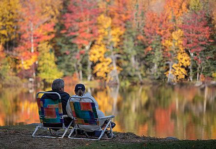 Two people admire the autumn colors reflected in the Echo lake in New Hampshire,United States of America Two people admire the autumn colors reflected in the Echo lake in New Hampshire,United States of America