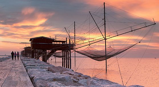Stilt fishermen on the sea at the dam of Sottomarina during the sunrise, Chioggia, venetian lagoon, Italy