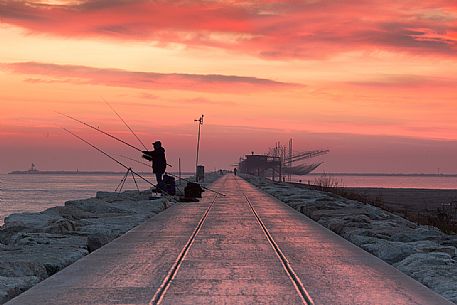 Fishermen at dawn along the pier of Sottomarina, Chioggia, venetian lagoon, Italy