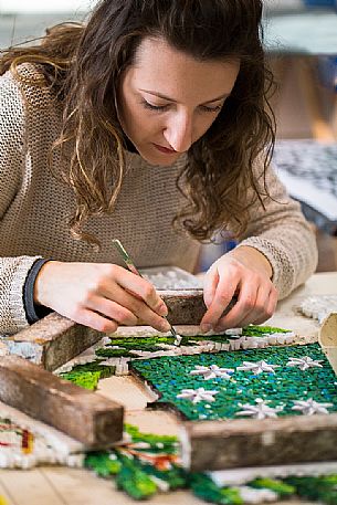 Young girl learns the art of mosaic in the oldest Mosaic School of Friuli , Italy