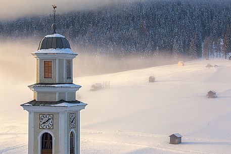 The parish church of Sesto and barns in the background during sunrise winter, Sesto, dolomites, Italy