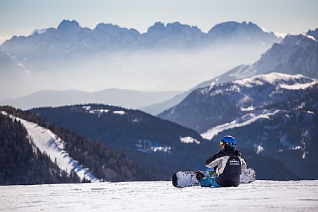 Snowboarder takes a break in front of the Comelico Dolomites, Sexten, Italy