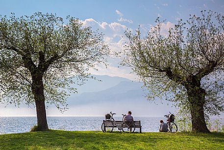 A bicycle couple relaxes in front of the panorama of Lake Garda in Malcesine, Italy