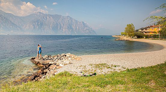 A couple embraces on a beach of Malcesine on Lake Garda, Italy
