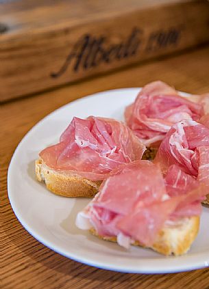 Prosciutto han and bread of the Casa del Prosciutto of the Alberti family in San Daniele del Friuli, Friuli Venezia Giulia, Italy