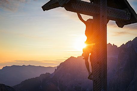 Crucifix illuminated by early dawn lights in the Tre Cime natural Park, South Tyrol, Dolomites, Italy