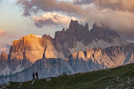 Two trekkers admire the sunset on the Croda Da Lago Mount, Cortina d'Ampezzo, Dolomites, Italy