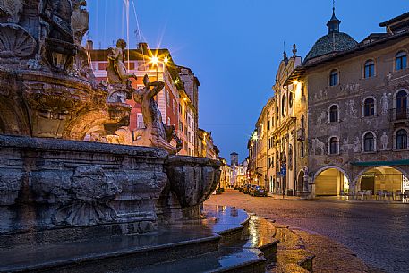 Detail of the fountain of Nettuno, on background the palaces in the Duomo square at twilight, Trento, Trentino Alto Adige, Italy