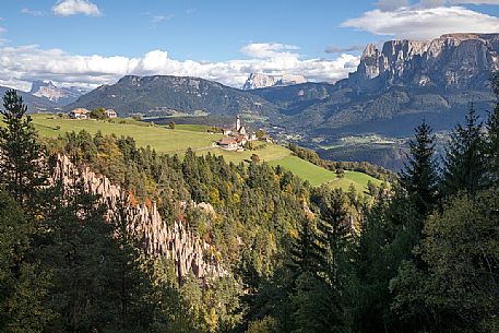 The earth pyramids of the Renon towards Mittelberg and San Nicol church, in the background the Sassolungo and Odle dolomites, Altopiano del Renon, Trentino Alto Adige, Italy, Europe