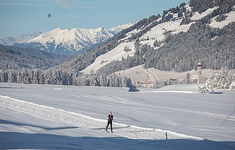 Cross-country skiing and in the background the bell tower and the small church of Villabassa, Pusteria valley, Trentino Alto Adige, Italy, Europe