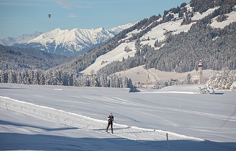 Cross-country skiing and in the background the bell tower and the small church of Villabassa, Pusteria valley, Trentino Alto Adige, Italy, Europe Cross-country skiing and in the background the bell tower and the small church of Villabassa, Pusteria valley, Trentino Alto Adige, Italy, Europe
