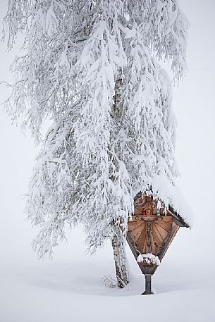 Crucifix surrounded by the snowy landscape of Sesto, dolomites, Pusteria valley, Trentino Alto Adige, Italy, Europe