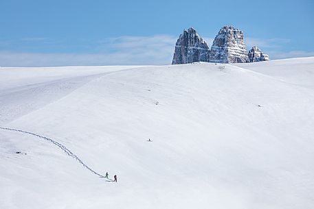 Trekkers with snowshoes descend from Mount Specie, in the background the Tre Cime di Lavaredo peak, Prato Piazza, Braies, Trentino Alto Adige, Italy, Europe