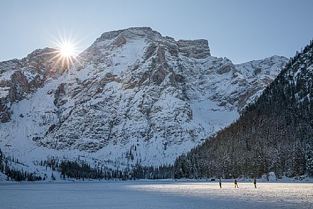 Tourists walk over the frozen lake of Braies, on background the Croda del Becco, Braies, Pusteria valley, Trentino Alto Adige, Italy