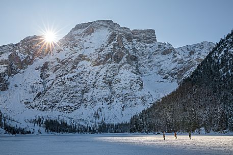 Tourists walk over the frozen lake of Braies, on background the Croda del Becco, Braies, Pusteria valley, Trentino Alto Adige, Italy Tourists walk over the frozen lake of Braies, on background the Croda del Becco, Braies, Pusteria valley, Trentino Alto Adige, Italy