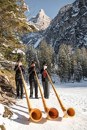 Musicians blowing alphorn on the shore of Braies lake during the Christmas markets of Braies, Pusteria valley, Trentino Alto Adige, Italy, Europe Musicians blowing alphorn on the shore of Braies lake during the Christmas markets of Braies, Pusteria valley, Trentino Alto Adige, Italy, Europe