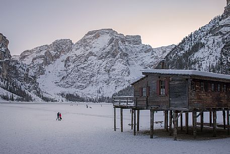 Tourists walk on the frozen Braies lake, on background the Croda del Becco mount, Braies, Pusteria valley, Trentino Alto Adige, Italy, Europe