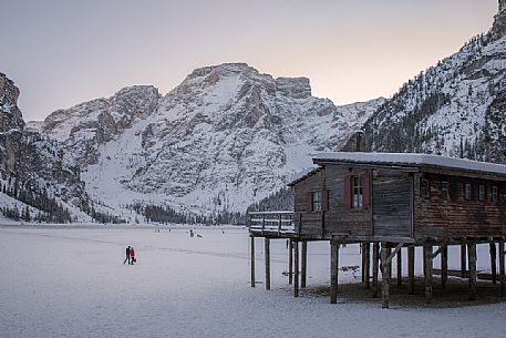 Tourists walk on the frozen Braies lake, on background the Croda del Becco mount, Braies, Pusteria valley, Trentino Alto Adige, Italy, Europe Tourists walk on the frozen Braies lake, on background the Croda del Becco mount, Braies, Pusteria valley, Trentino Alto Adige, Italy, Europe
