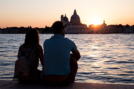 A couple of tourists admires the sun goes down from Saint Giorgio island, Venice, Italy, Europe