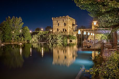 Terrace of the restaurant in Borghetto village by night, in the background the Visconteo bridge, Valeggio sul Mincio, Veneto, Italy, Europe Terrace of the restaurant in Borghetto village by night, in the background the Visconteo bridge, Valeggio sul Mincio, Veneto, Italy, Europe