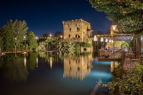 Terrace of the restaurant in Borghetto village by night, in the background the Visconteo bridge, Valeggio sul Mincio, Veneto, Italy, Europe