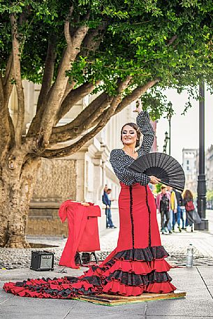 Woman in traditional costume dances flamenco in the streets of the Barrio Santa Cruz, Seville, Spain, Europe Woman in traditional costume dances flamenco in the streets of the Barrio Santa Cruz, Seville, Spain, Europe