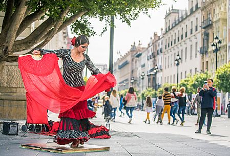 Woman in traditional costume dances flamenco in the streets of the Barrio Santa Cruz, Seville, Spain, Europe Woman in traditional costume dances flamenco in the streets of the Barrio Santa Cruz, Seville, Spain, Europe