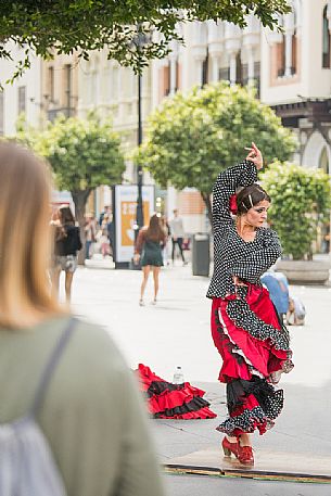 Woman in traditional costume dances flamenco in the streets of the Barrio Santa Cruz, Seville, Spain, Europe Woman in traditional costume dances flamenco in the streets of the Barrio Santa Cruz, Seville, Spain, Europe