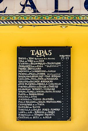 Tapas menu, typical Spanish food displayed outside a bar in the Barrio de Santa Cruz, Seville, Andalusia, Spain, Europe