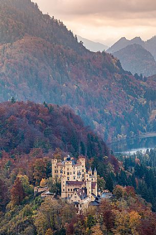 The Hohenschwangau castle, Schloss Hohenschwangau, with lake Alpsee and Tannheim Mountains, Schwangau near Fuessen, , surrounded by autumn colors, Bayern, Germany, Europe