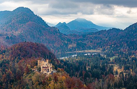 The Hohenschwangau castle, Schloss Hohenschwangau, with lake Alpsee and Tannheim Mountains, Schwangau near Fuessen, surrounded by autumn colors, Bayern, Germany, Europe