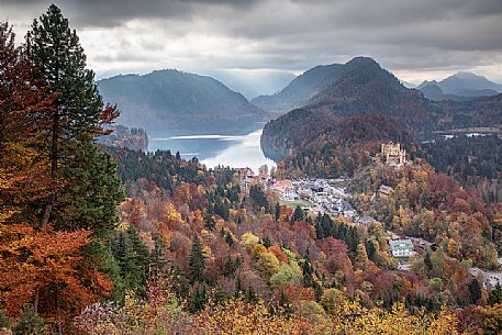 The Hohenschwangau castle, Schloss Hohenschwangau, with lake Alpsee and Tannheim Mountains, Schwangau near Fuessen, surrounded by autumn colors, Bayern, Germany, Europe