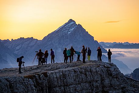 Tourists photograph the sun rising nearby Lagazuoi refuge, on background the Antelao Mount, Cortina d'Ampezzo, Veneto, Italy, Europe