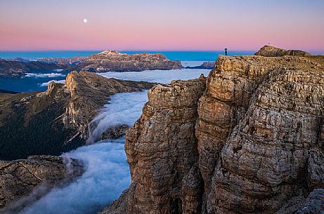 Hiker looks the moon rising and the clouds wrap around the landscape nearby Lagazuoi Refuge, Cortina d'Ampezzo, Veneto, Italy, Europe