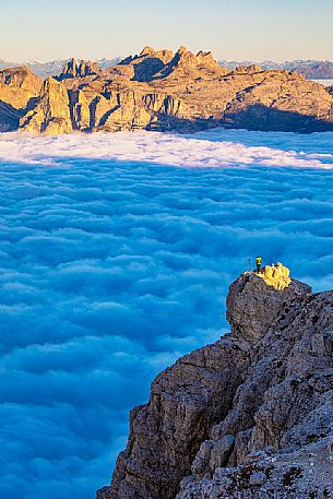 Photographer looks the sunrise towards the Odle Puez natural park and the clouds wrap around the landscape nearby Lagazuoi Refuge, Cortina d'Ampezzo, Veneto, Italy, Europe
