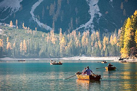 Tourists on boat in the Braies lake with autumn colors, dolomites, Pusteria valley, Trentino Alto Adige, South Tyrol, Italy, Europe