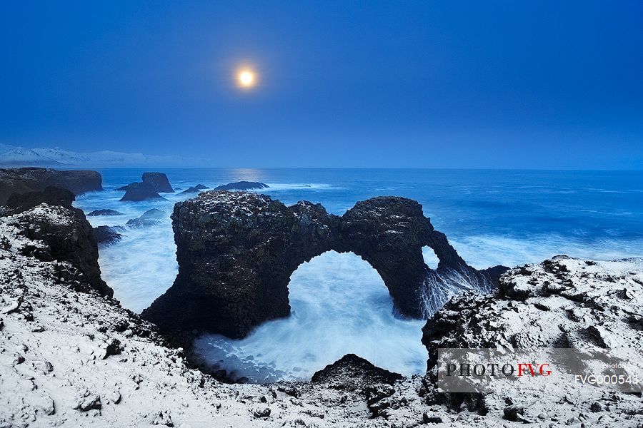 The full moon, the snow freshly fallen on the coast and the blue light after the sunset make this Arnarstapi landscape unique.
