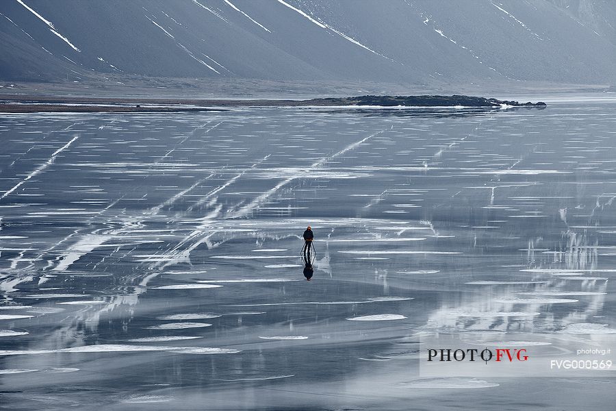 A risk lover photographer takes picture from the middle a frozen lagoon