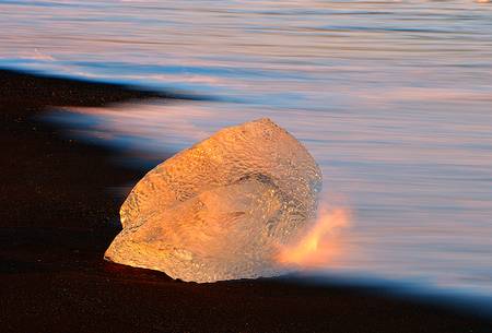 A little piece of ice becomes like gold thanks to the warm light of the sunrise