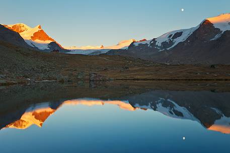 Fluhalp shelter is surrounded by amazing mountains, everything is reflected into the sharp surface of Stellisee Lake