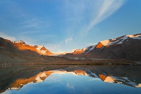 Fluhalp shelter is surrounded by amazing mountains, everything is reflected into the sharp surface of Stellisee Lake