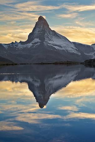 The great summit of the Matterhorn with its beautiful shape, emerges from the water during sunset of Stellisee