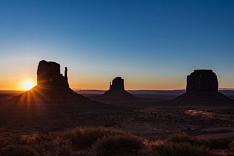The sun rising on the background of The Mittens and Merrick Butte  from John Wayne's Point the Oljato Navajo Monument Valley, Arizona USA 