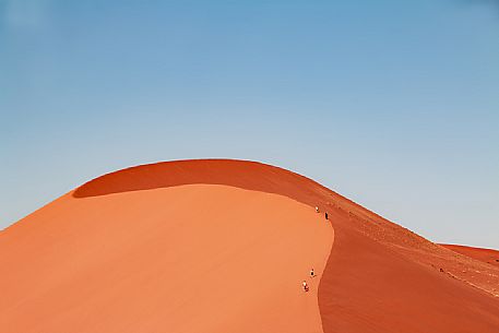 Group of small human figures climbing the Dune 45 to the top, Namib Naukluft National Park, Namibia, Africa